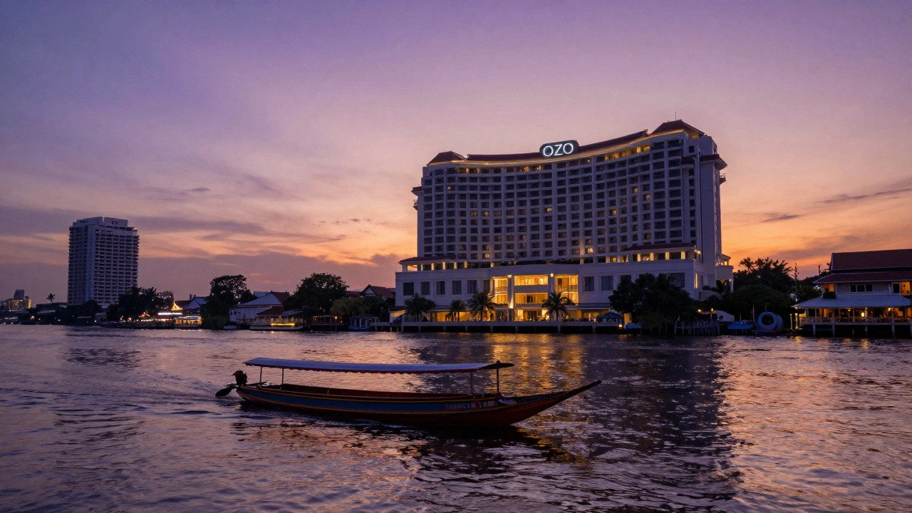 Sunset view of modern riverside hotel on Chao Phraya River with passing long-tail boat